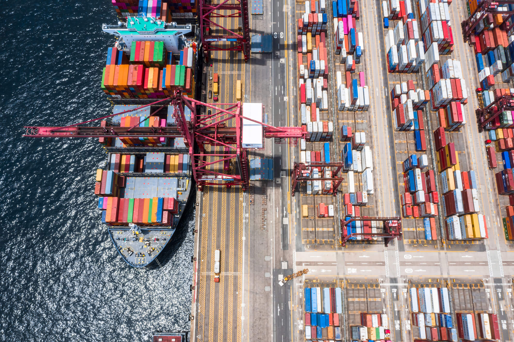 Photography of a cargo boat docked in a port filled with containers